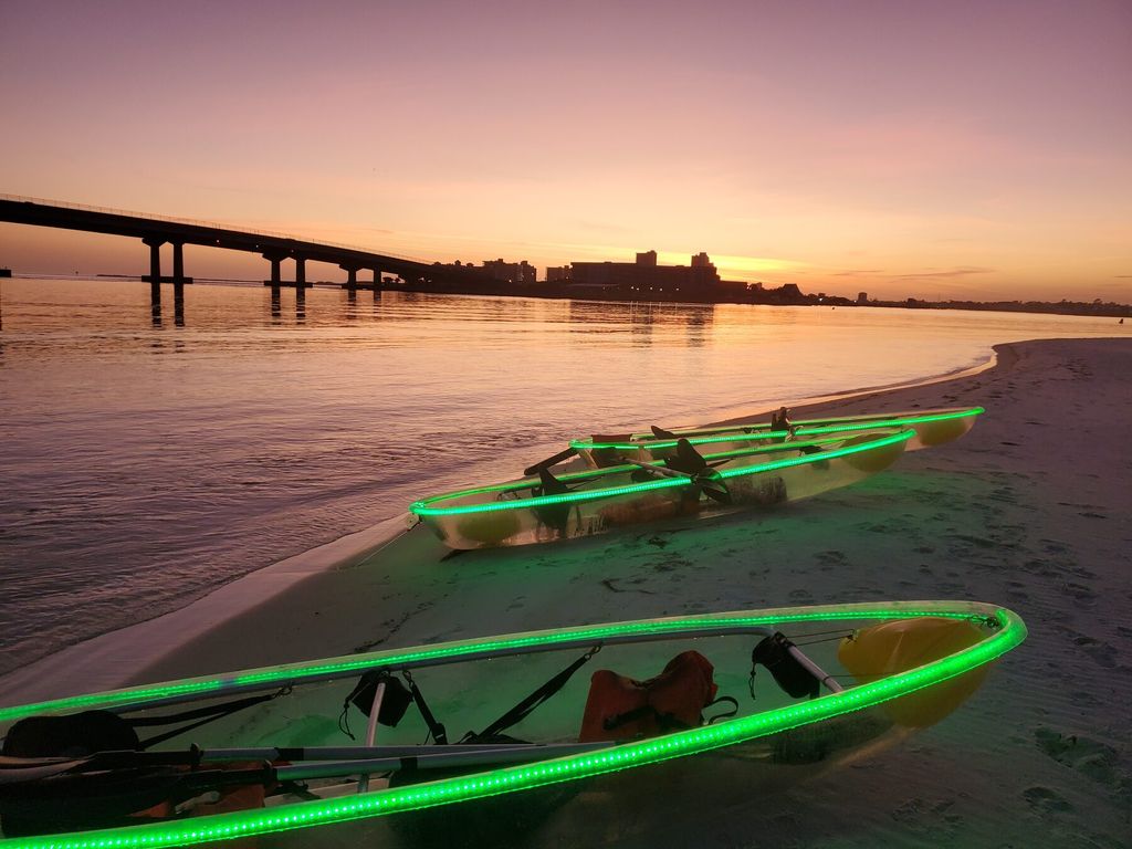 Clear kayaks glowing green on the sand at sunset