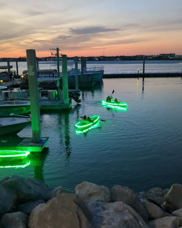 Glowing kayaks out on the marina water at sunset, seen from the rocks