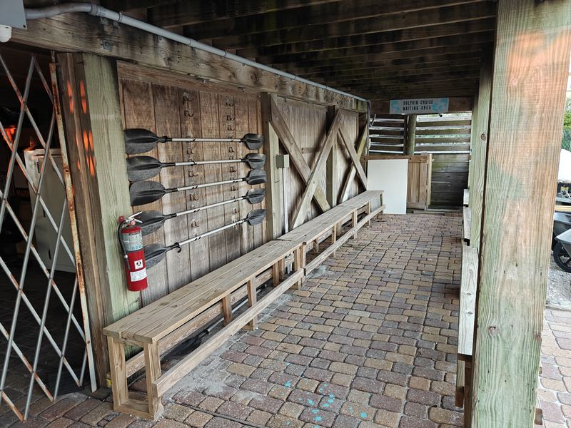 The Sea View Tours check-in spot at Caribe Marina: a covered wooden walkway with paddles on the wall, benches and brick pavers